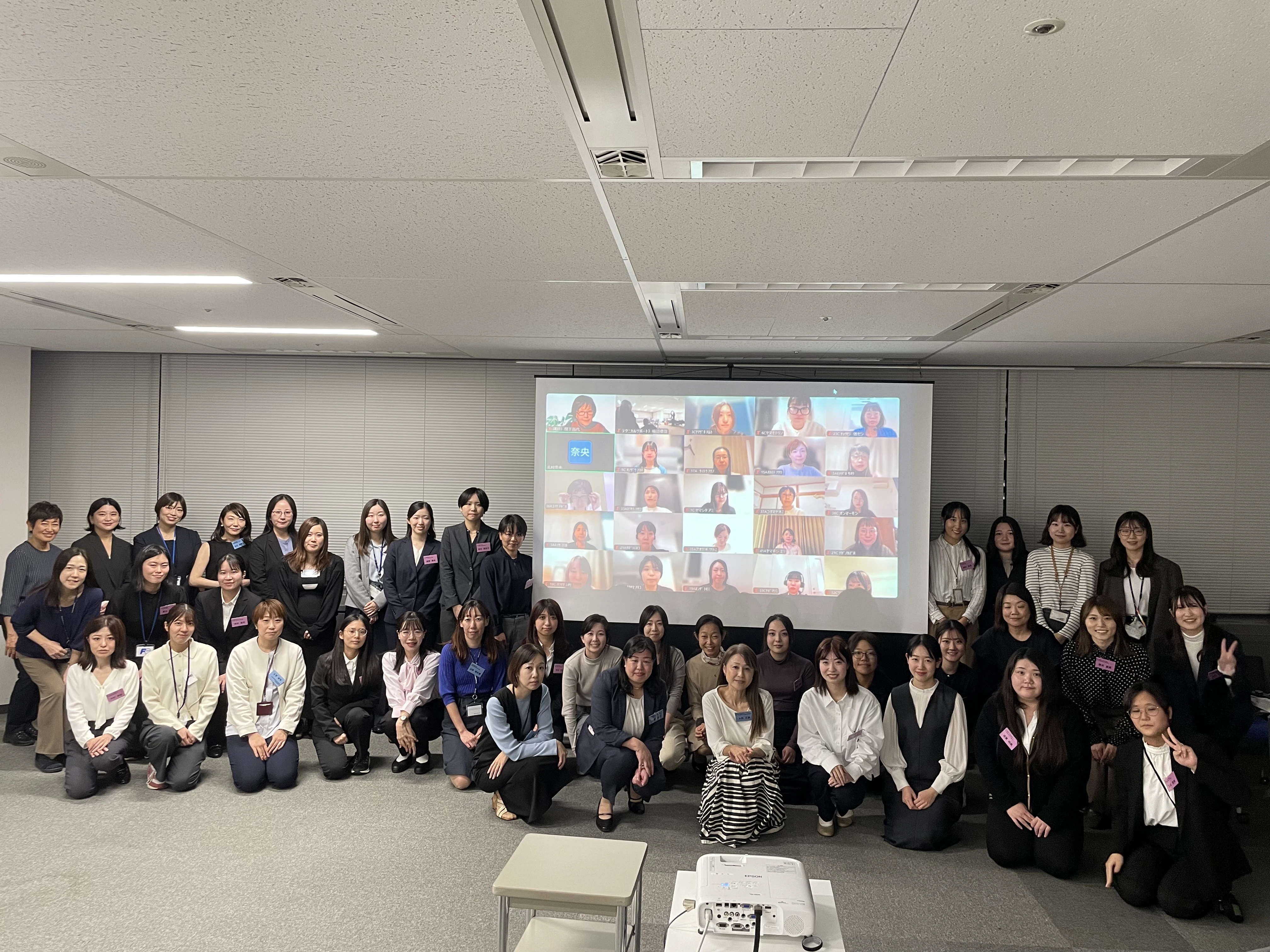第15期シスター制度キックオフの集合写真。多数の女性社員がスクリーンの前に集まっている様子