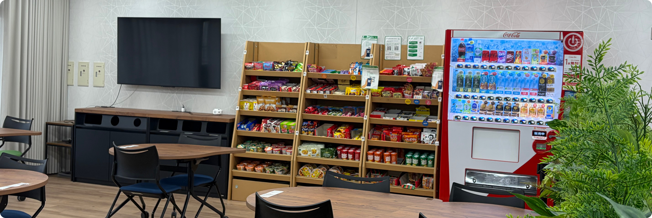 お菓子やカップ麺が豊富に並ぶ棚や自動販売機、リラックスできるテーブル席などが設置されたスペースの様子