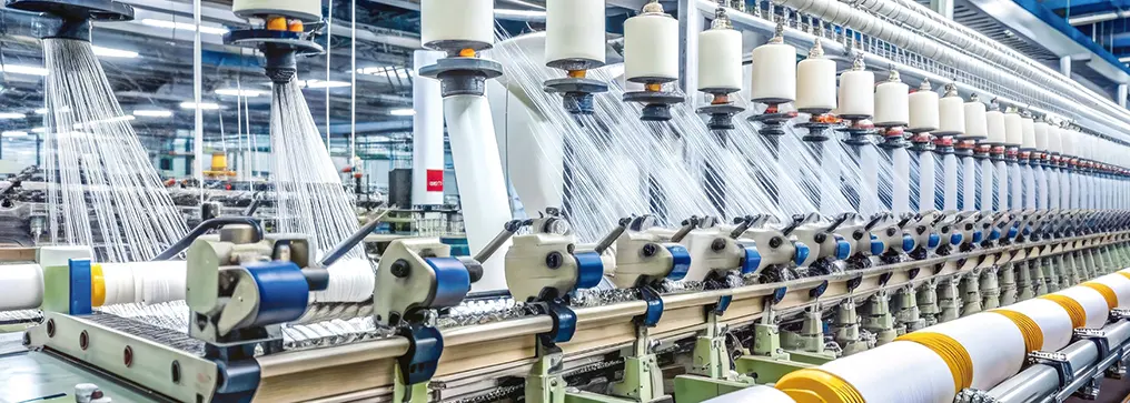 繊維工場で糸を紡ぐラインの様子を示す画像。安定した回転制御と品質向上を支援することを表している。